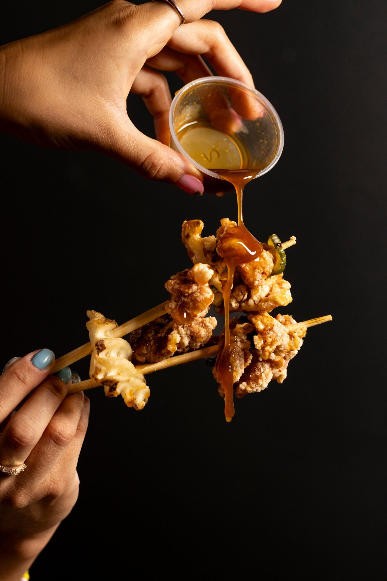 Sauce poured over karaage held in chopsticks