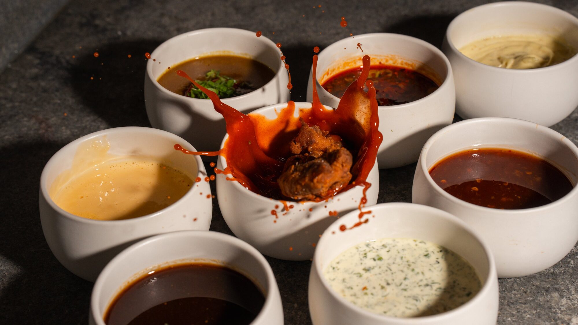 Karaage splashing into a cup of red sauce