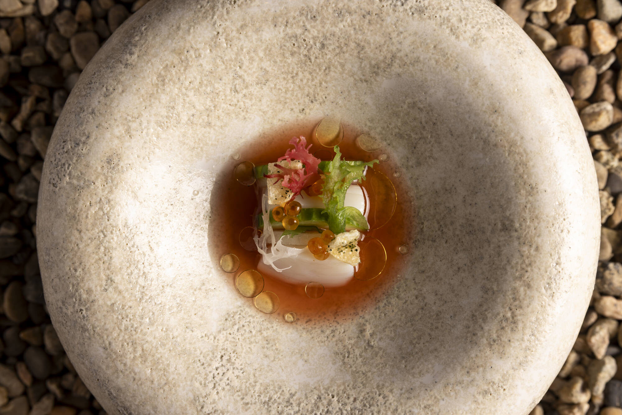 Scallop in a chilled broth on a stone bowl